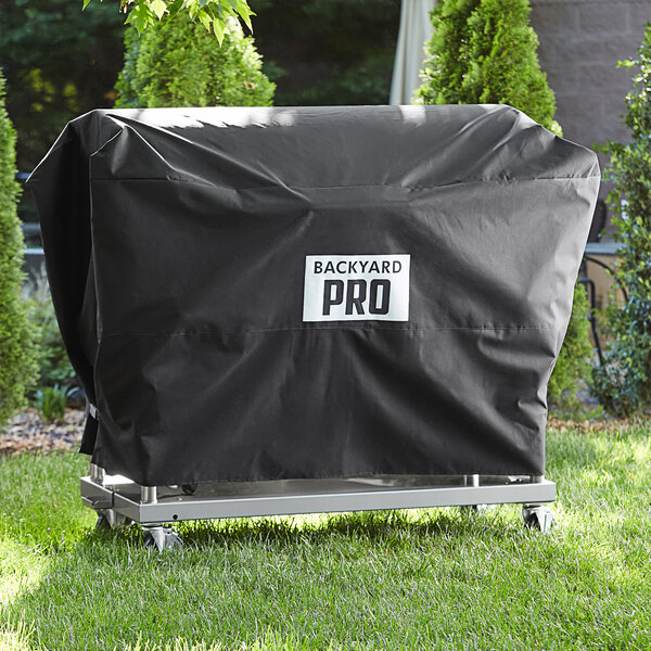 A black Backyard Pro vinyl cover on a metal cart in a yard.