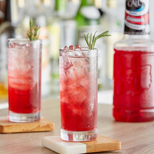 A glass of Finest Call Cranberry Juice with ice and a rosemary sprig.
