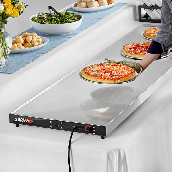 A buffet table with a ServIt heated shelf full of pizza plates.