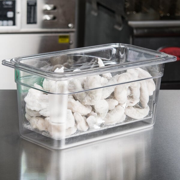 A Cambro clear plastic container with food inside sitting on a counter.