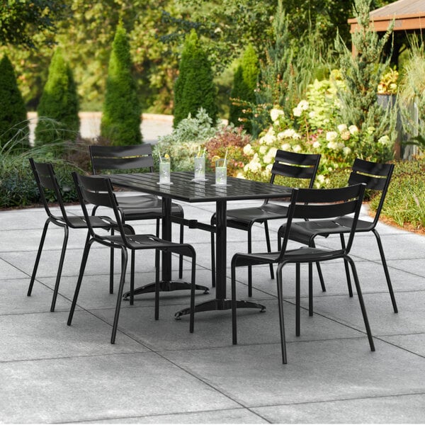 A Lancaster Table & Seating black outdoor table with chairs on a patio.