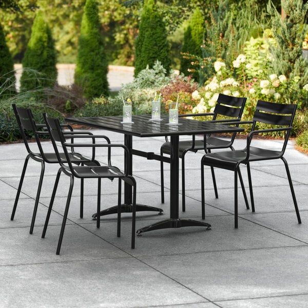 A Lancaster Table & Seating black aluminum table with chairs and umbrella on an outdoor patio.