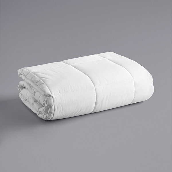 A white Oxford cotton and polyester duvet insert folded up on a gray surface.