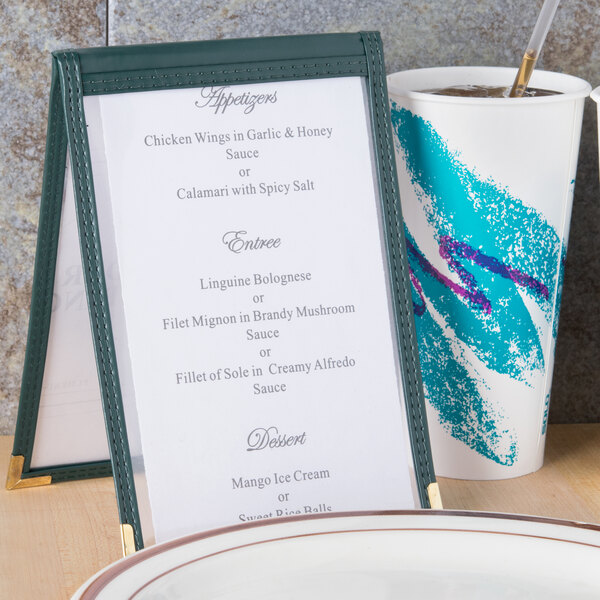 A Menu Solutions green sewn edge table tent with a menu on a table.