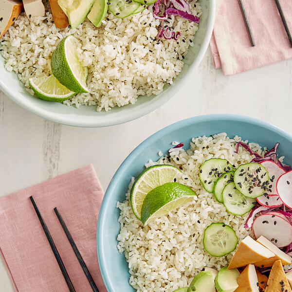 A bowl of Golden Tiger Cilantro Lime Rice with lime wedges and vegetables.