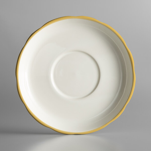 A white saucer with a scalloped edge and gold trim.
