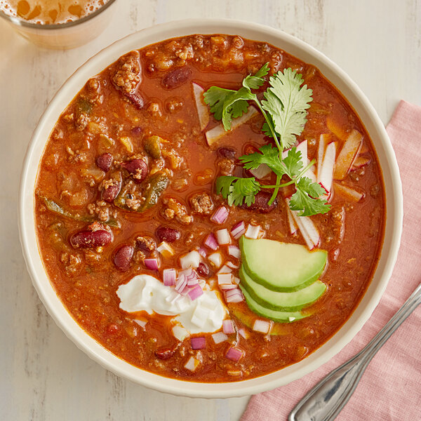A bowl of Whitey's Beef Chili with beans topped with sour cream and avocado.