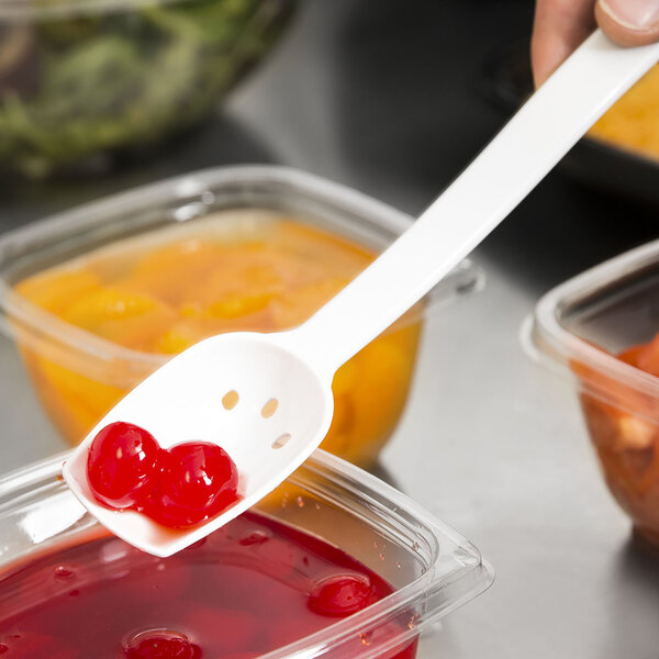 A white plastic Thunder Group salad bar spoon with red cherries in it.