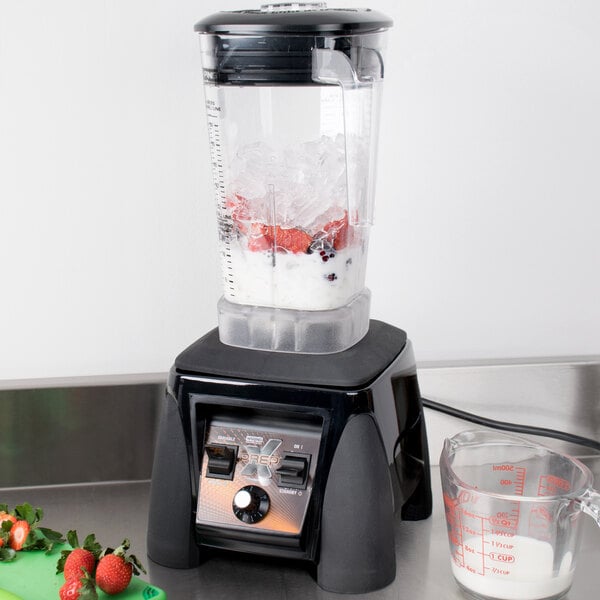 A Waring X-Prep blender on a counter with a blender of ice and strawberries.