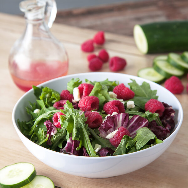 A white Carlisle melamine bowl filled with salad, raspberries, and cucumbers.