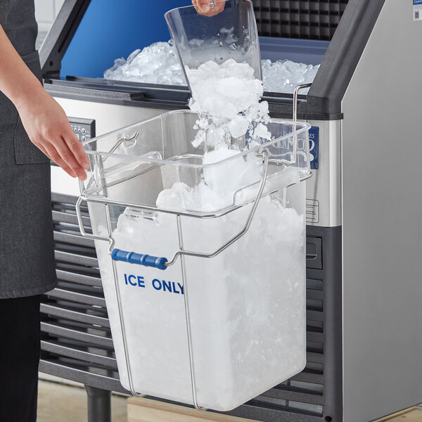 A woman pouring ice from a square container into an ice machine.