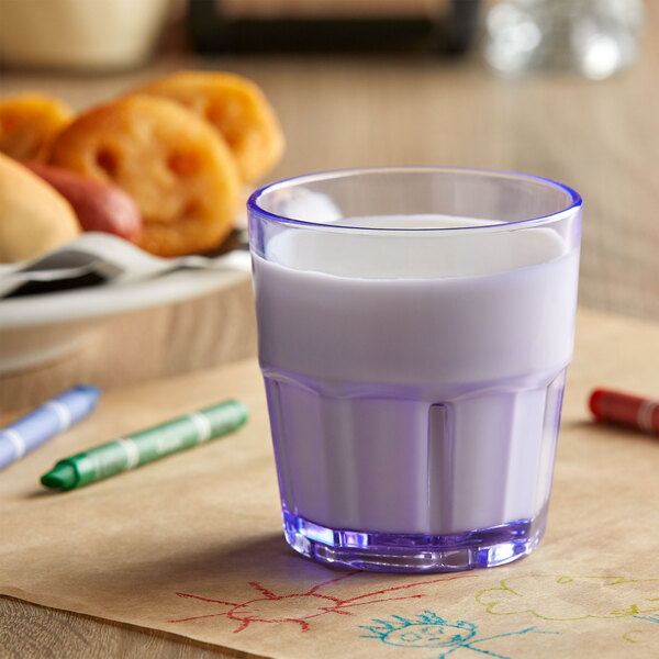 A blue Bahama plastic tumbler filled with milk on a table.