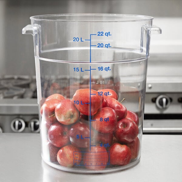 A Carlisle clear round polycarbonate food storage container full of apples.