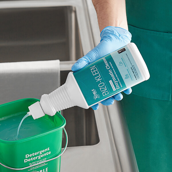 A person in blue gloves pouring Noble Eco Enzo-Kleen into a green bucket.
