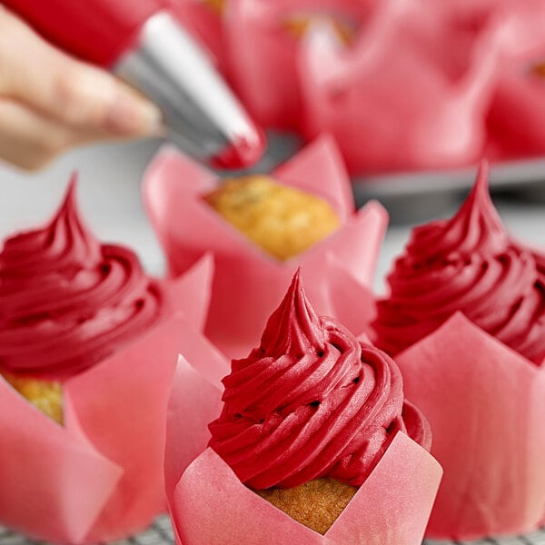 A close-up of a cupcake with pink frosting using Chefmaster Super Red Gel Food Coloring.