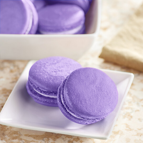 A white plate of purple macaroons with a Chefmaster Natural Violet Liqua-Gel Food Coloring.