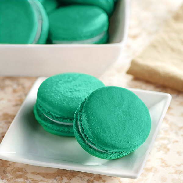 A white plate with green macaroons with Chefmaster Natural Dark Green Liqua-Gel Food Coloring on it.