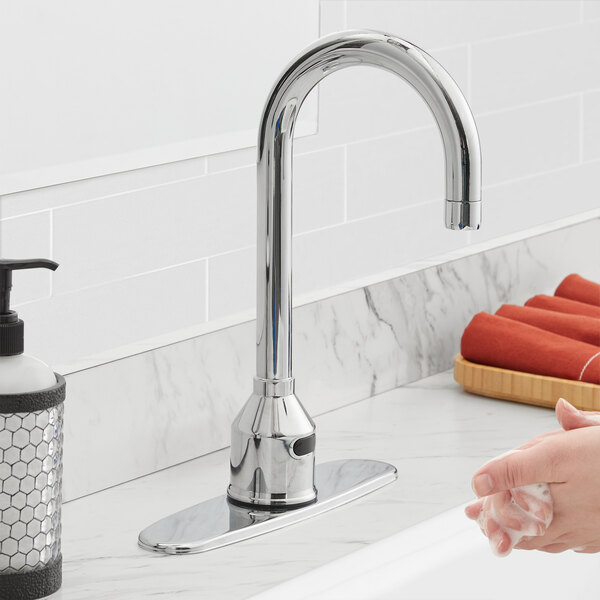 A person washing their hands with a silver Waterloo hands-free faucet.