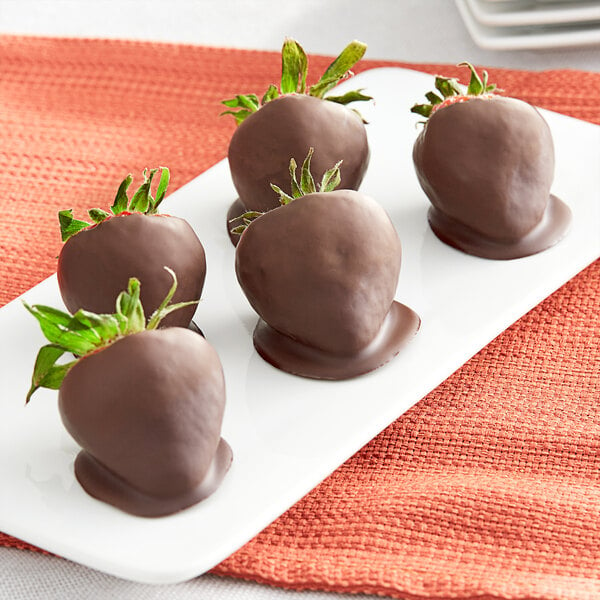 A plate of Ghirardelli chocolate covered strawberries on a white surface.