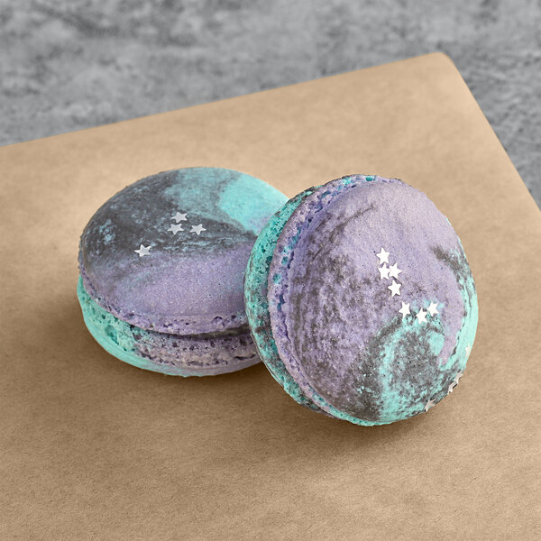 Two Galaxy Macarons with purple and blue stars on them.