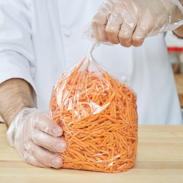 A person in gloves holding an LK Packaging plastic food bag of shredded carrots.
