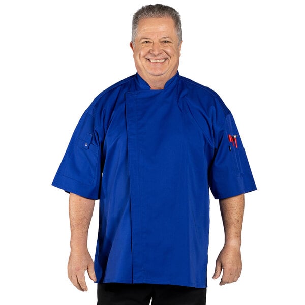 A man wearing a deep royal blue Uncommon Chef short sleeve chef coat with mesh back.