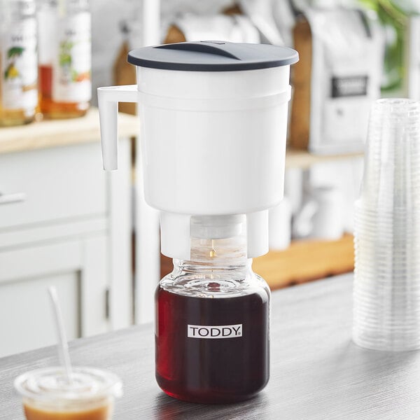 The Toddy Cold Brew System on a table with a pitcher of liquid and a cup.