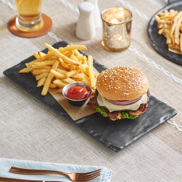 An Acopa faux slate melamine serving board with a burger and fries on it.