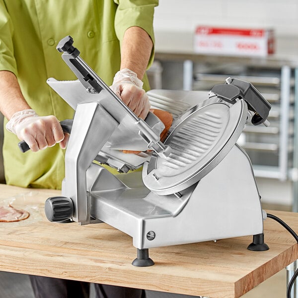A person using a Centerline by Hobart manual meat slicer to cut meat.