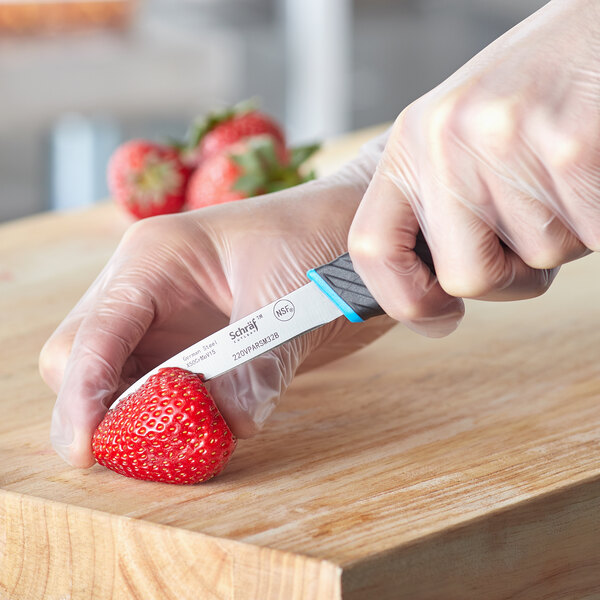 A person using a Schraf smooth edge paring knife to cut a strawberry.