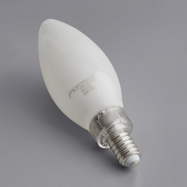 A TCP frosted LED filament light bulb with a silver base on a gray surface.