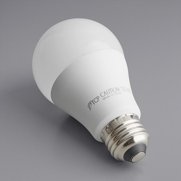 A TCP 11.5W dimmable LED light bulb with a round metal base on a gray surface.
