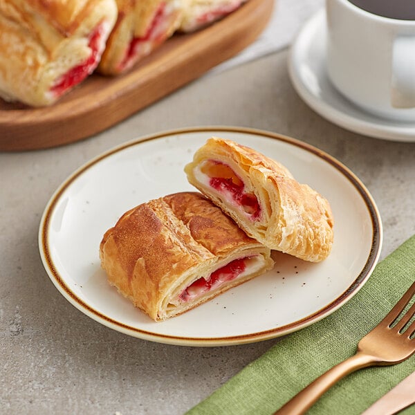 A plate with two Orange Bakery strawberry cream cheese filled croissants and a cup of coffee.
