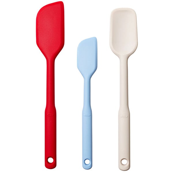A group of OXO Good Grips spatulas with red, blue, and white handles.
