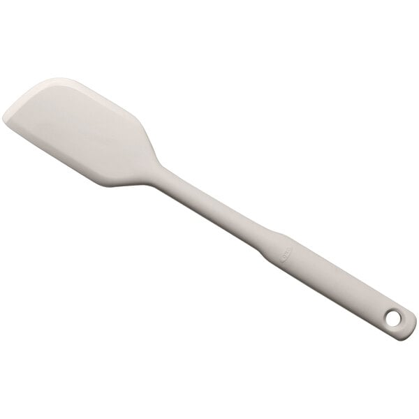 An OXO Good Grips white silicone spatula with a hole in the handle.