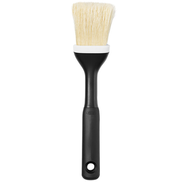 An OXO Good Grips pastry and basting brush with a black plastic non-slip grip and white bristles.