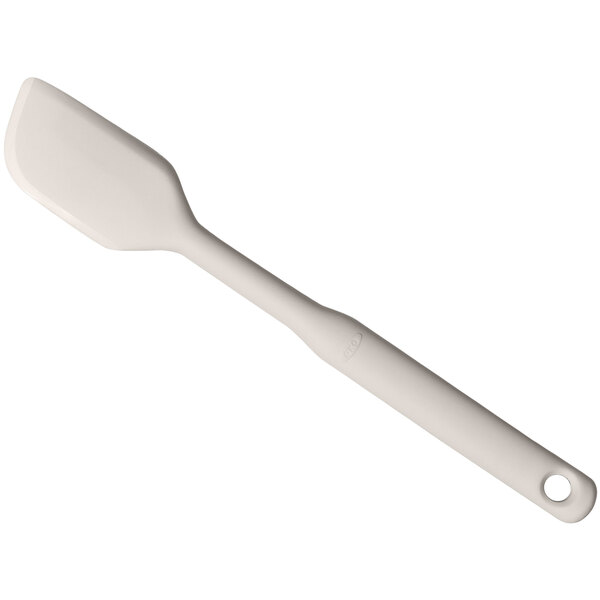 An OXO Good Grips beige silicone spatula with a white handle and hole.