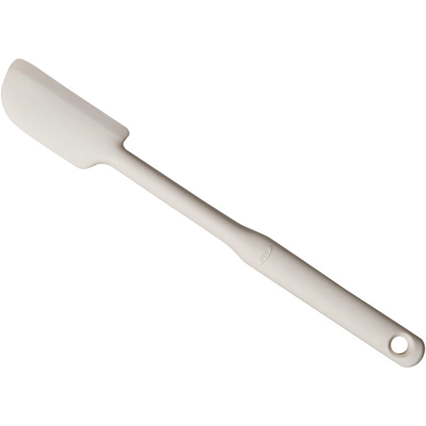 An OXO Good Grips beige silicone jar spatula with a white handle.