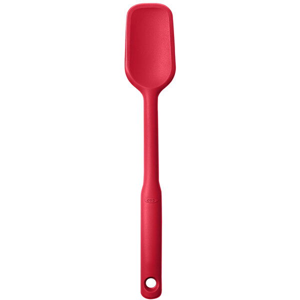 An OXO red silicone spoonula with a handle and hole on a white background.
