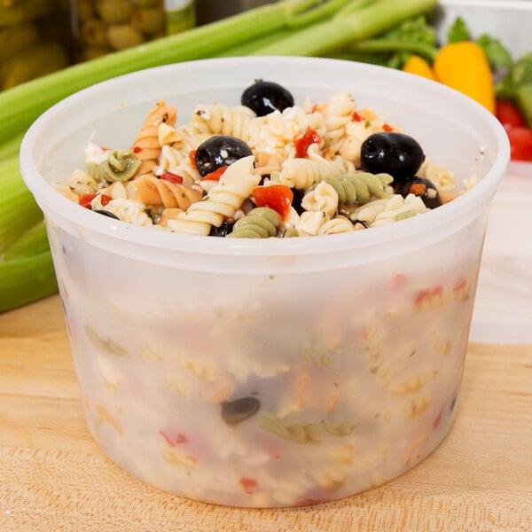 A translucent ChoiceHD deli container filled with pasta salad on a table.