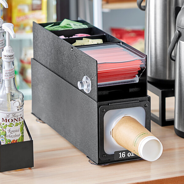 A black KleanTake countertop cup dispenser with a stirrer slot.