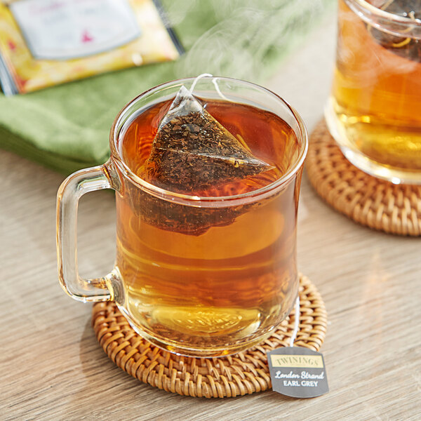 A glass mug of Twinings Earl Grey tea with a tea bag in it.