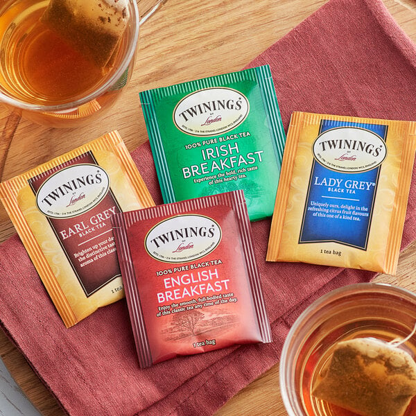 A group of Twinings black tea packets on a table with a cup of tea.