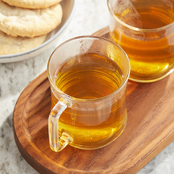 A wooden tray with two Twinings Pure Chamomile Tea K-Cups next to a glass mug of tea.