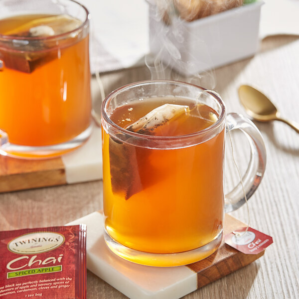 A glass mug of Twinings Spiced Apple Chai tea with a tea bag in it.