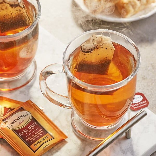 A glass mug of Twinings Earl Grey Extra Bold tea with a tea bag in it.