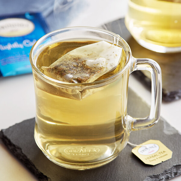 A glass mug of Twinings Nightly Calm tea with a tea bag in it.
