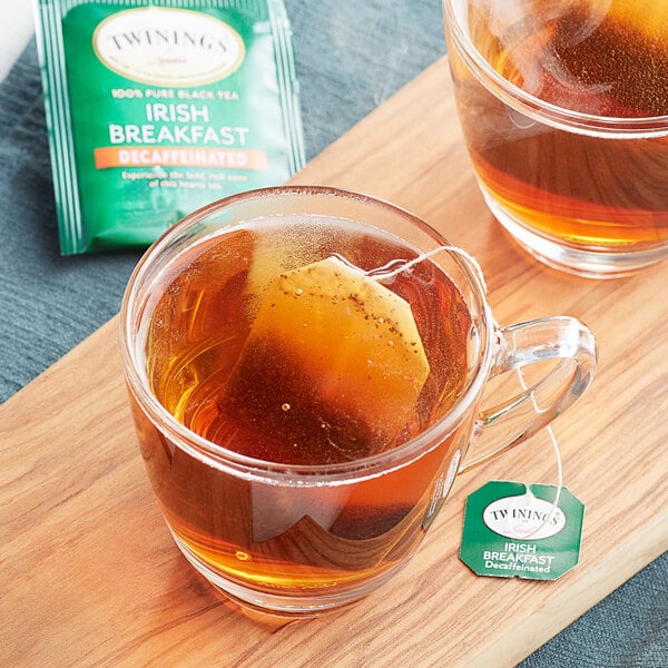 A glass mug of Twinings Irish Breakfast decaffeinated tea with a tea bag in it.