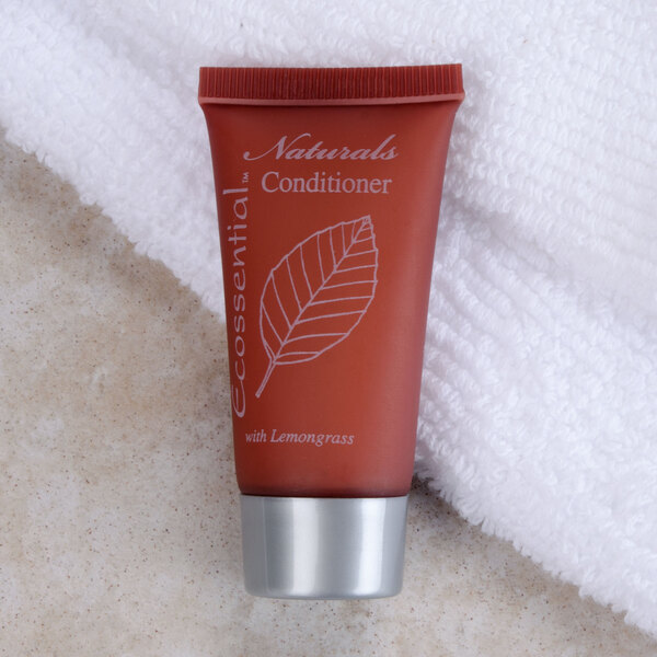An Ecossential Naturals hotel conditioner bottle on a towel with a white leaf drawing.
