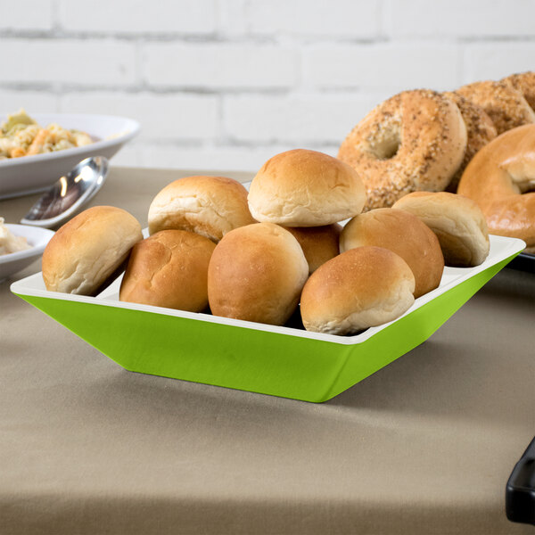 A table with rolls of bread and a GET Keywest square melamine bowl filled with food.